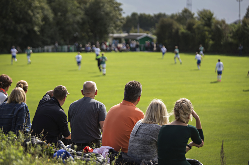 Forældre kigger på børn, der spiller fodbold.