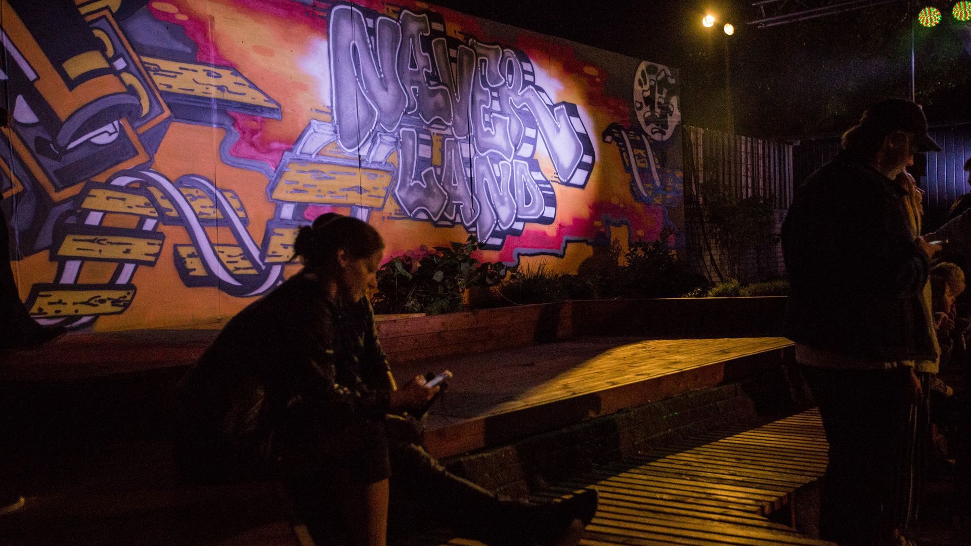 En Kvinde Sidder Med sin telefon Foran Graffitivæg