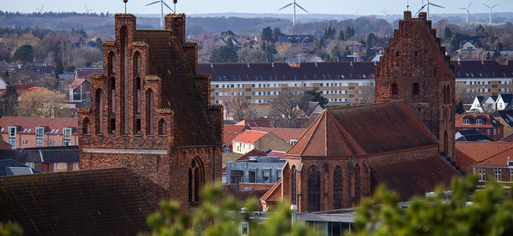 Dronefoto af Næstved Kirkes tårne og vindmøller i baggrunden