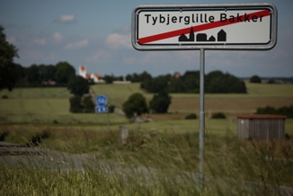 Byskilt på vej ud ad Tybjerg med gule marker i baggrunden