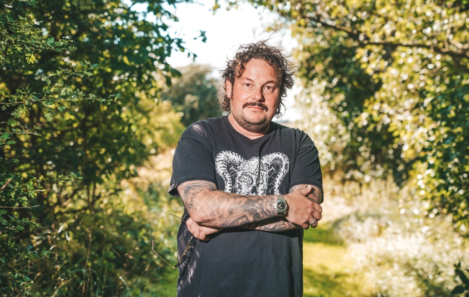 Michael Hvolgaard Andersen står med korslagte arme foran et grønt område