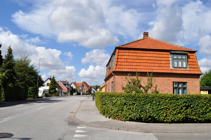 Billed af den privatvej som støder op til en offentligvej med huse ved vejen