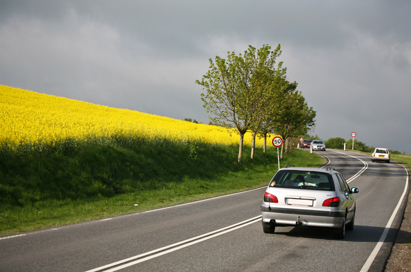 Bil kører på vej med en gul mark til venstre