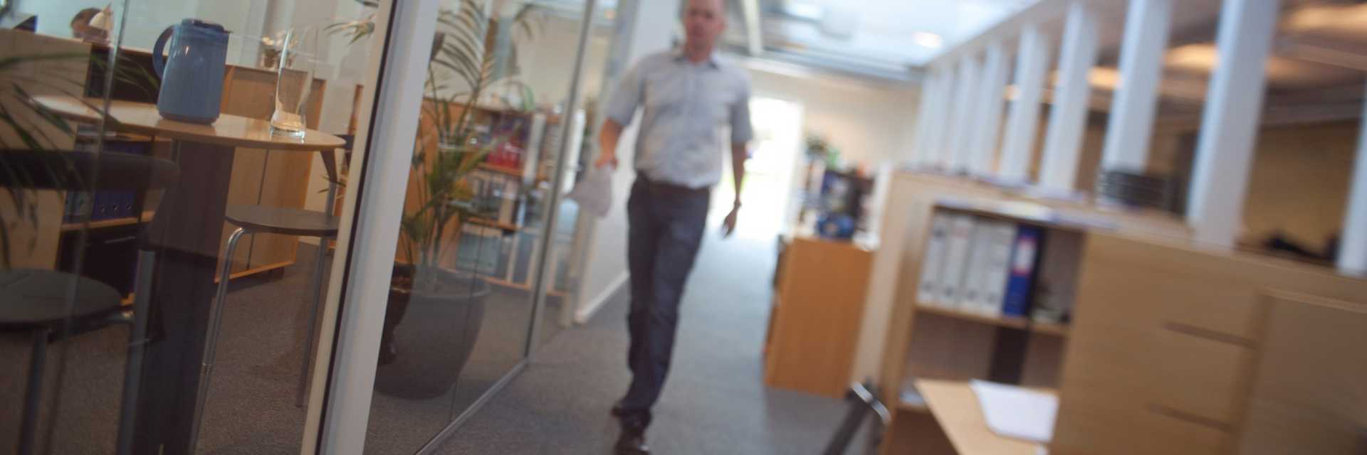 En mand går på gangen i en kontormiljø
