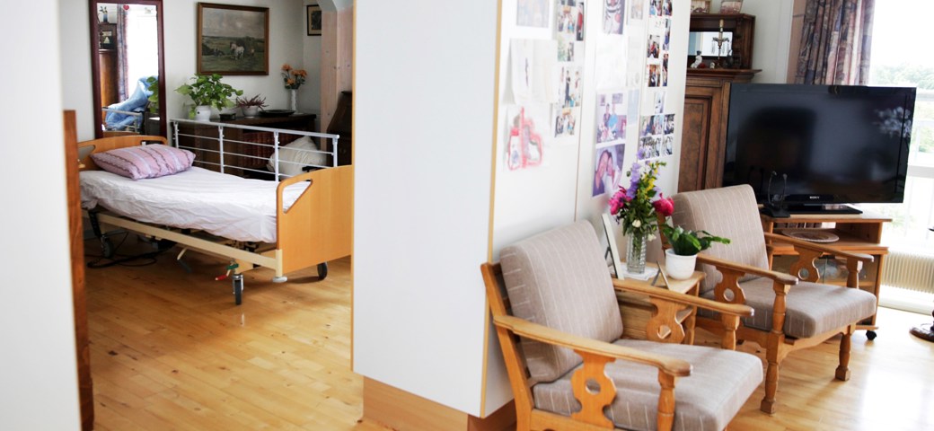 Bolig på Birkebjergcenterets 3. sal,  der viser lænestole, fjernsyn og skillevæg med soveværelse bagved