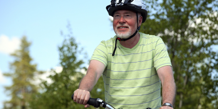 På billedet ses en gråskægget mand med cykelhjelm og cykel