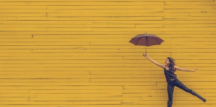 Person bruge en paraply som balanceredskab - gul baggrund
