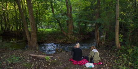 To Piger sidder på et tæppe i Skoven Ved Mogenstrup