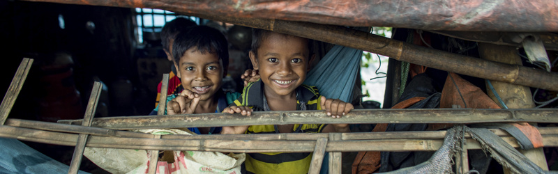 Børn kigger ud gennem presenninger i Bangladesh