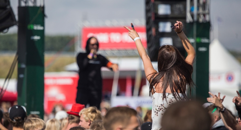 En kvinde blandt publikum sidder på skuldrene og gestikulerer mod en mandlig rapper på scenen