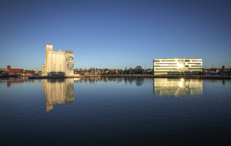 Maxbank-bygningen og siloer spejlet i Næstved havn