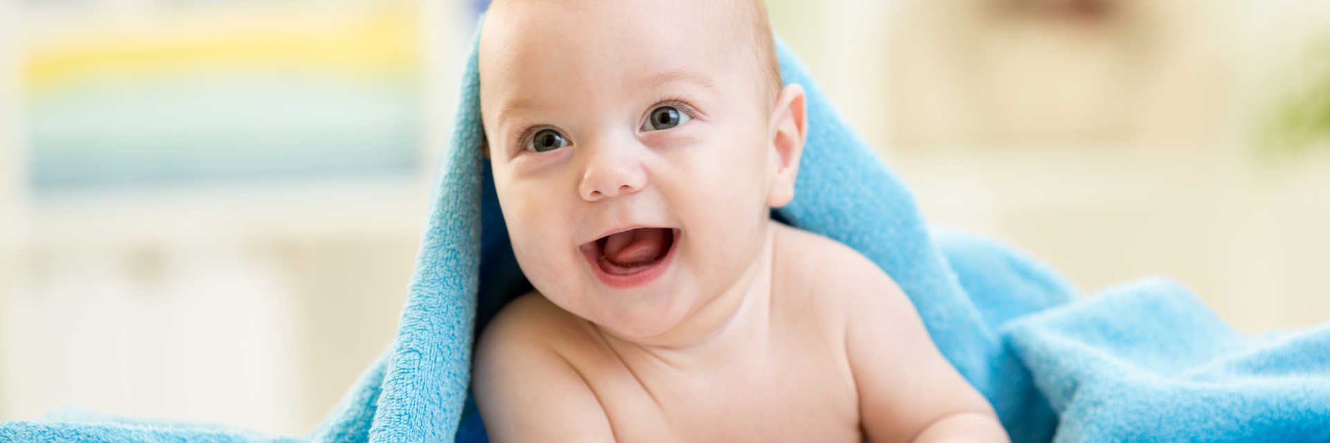 Baby der smiler under blåt håndklæde