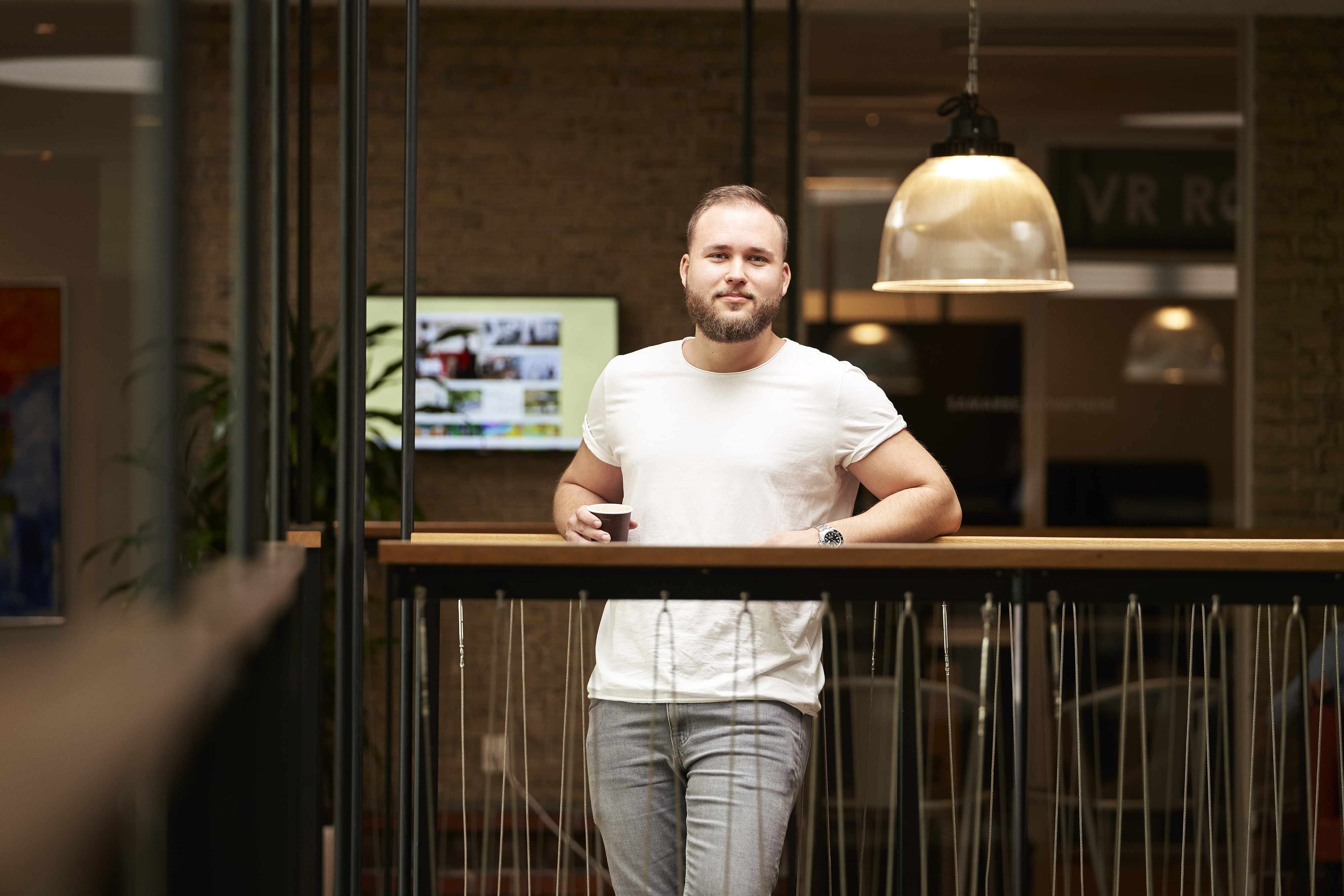 En mand med en hvid t-shirt står ved et gelænder