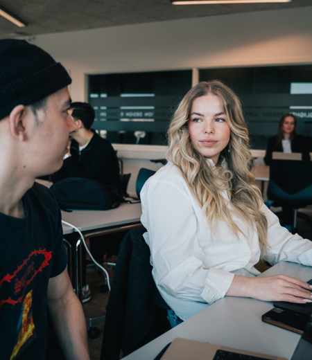 To elever arbejder sammen med hver deres computer To elever arbejder sammen med hver deres computer
