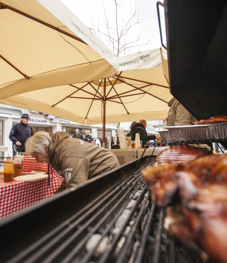 Kød på grill, parasoller og personer i baggrunden. Kød på grill, parasoller og personer i baggrunden.