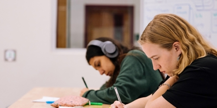To personer sidder ved et bord og arbejder på opgaver
