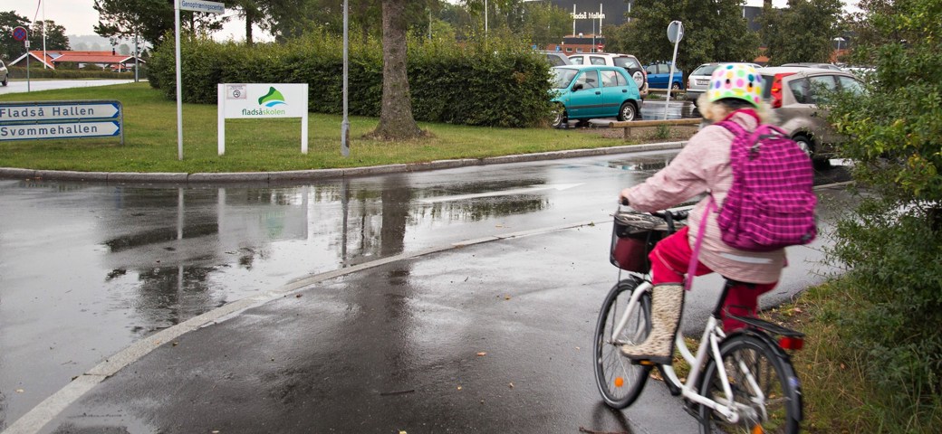 Pige på cykel drejer ad vejen mod Fladså skole og Hallen