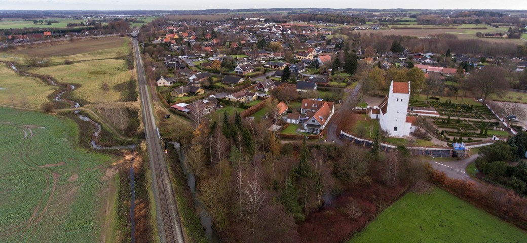 Holme Olstrup dronebillede af togskinner og kirken bagved