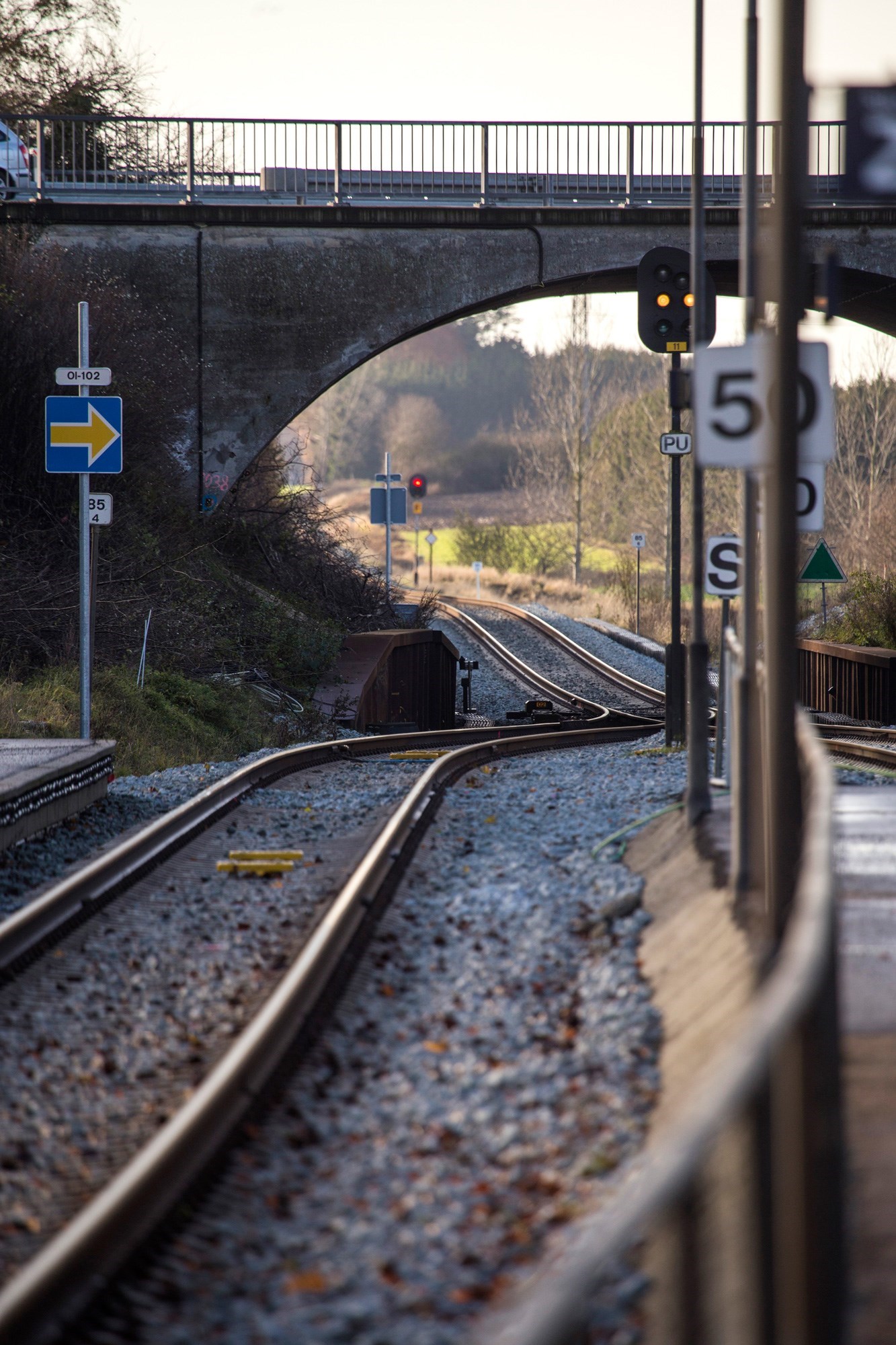 Togskinnerne går under en lille bro ved Holme Olstrup Station