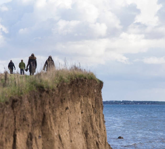 Mennesker på vej væk fra klint ved vandet 