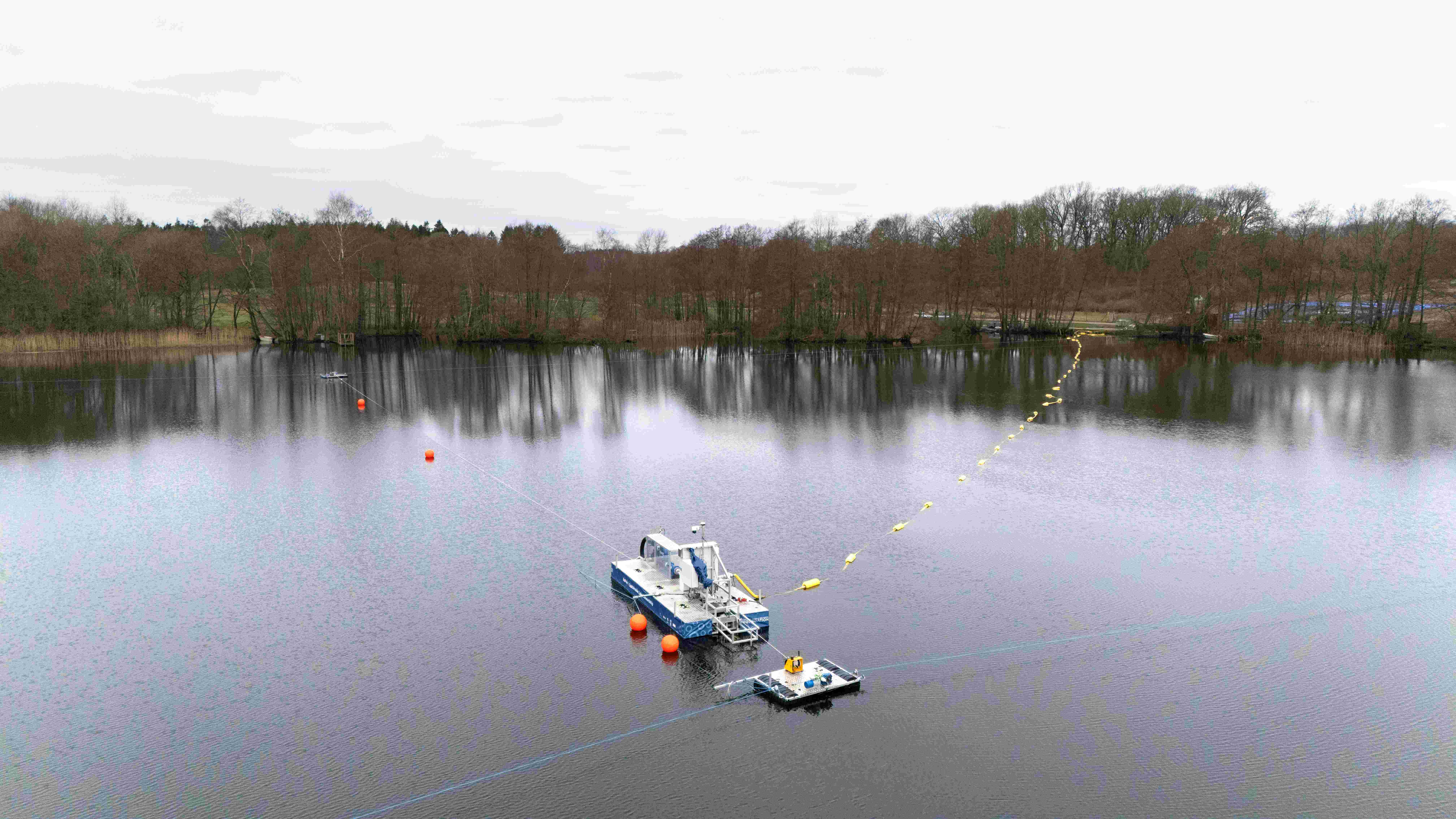 Foto af en sø, hvor Sørobotten og dens hjælpeflåde er sat op og i aktion. 