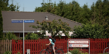 Et barn på cykel foran byskilte i Fensmark