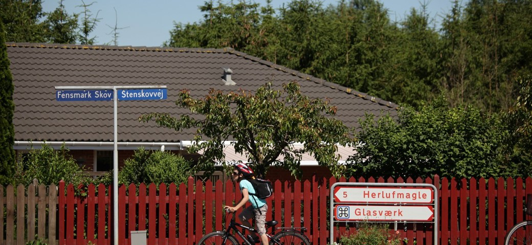 Et barn på cykel foran byskilte i Fensmark