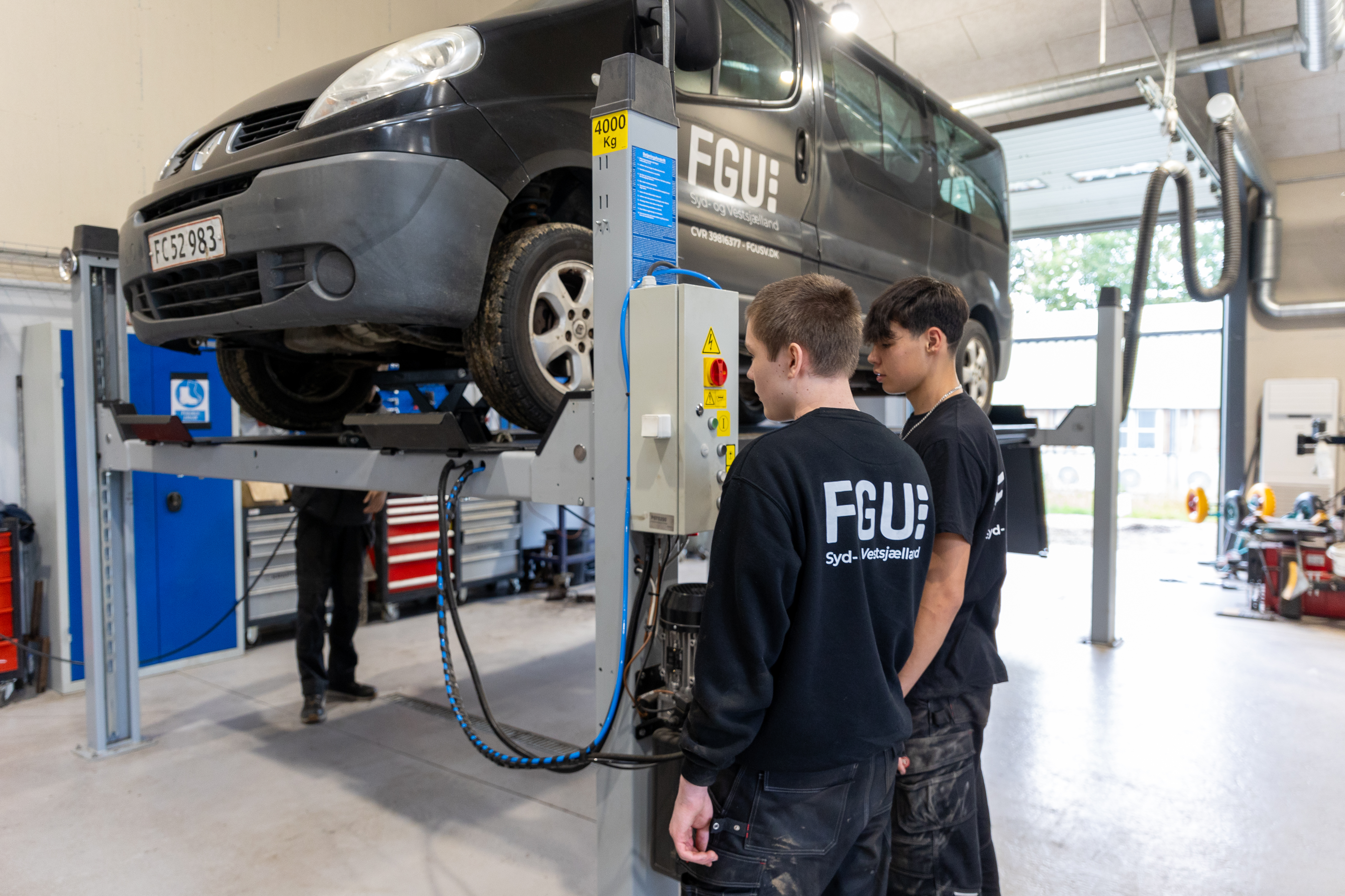 To drenge arbejder med en sort bil 