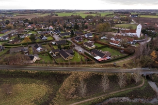 Dronebillede Af Togskinner foran by og kirke i Holme Olstrup