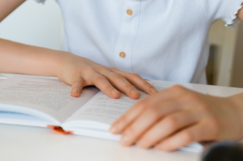 et barn der sidder med en åben bog mellem hænderne