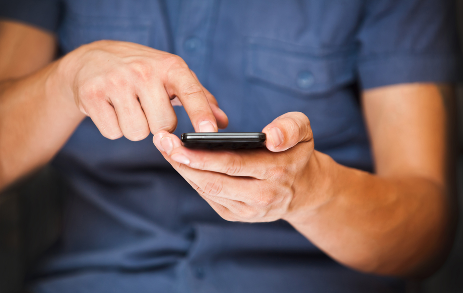 Mand der holder en mobiltelefon