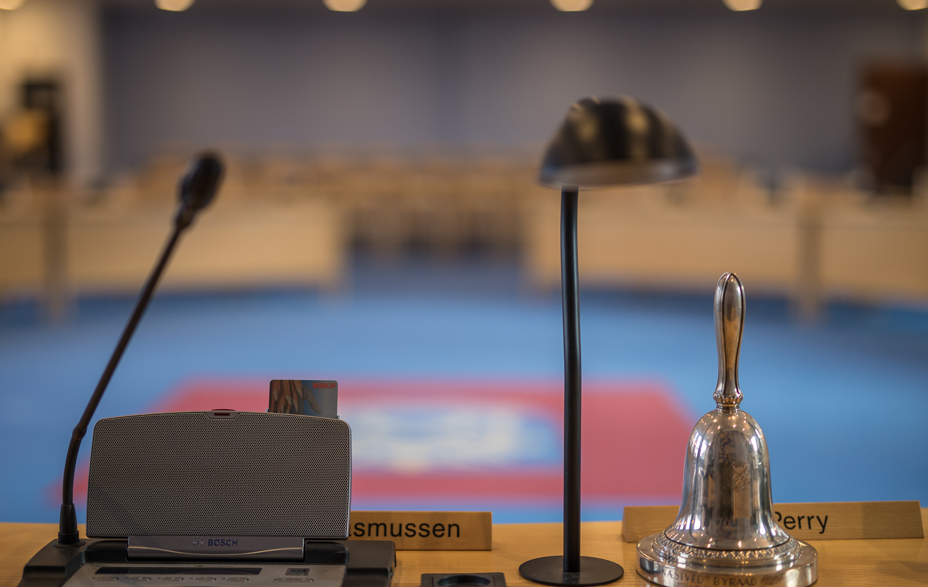Byrådssalen med bord, mikrofon, lampe og klokke - formandens plads