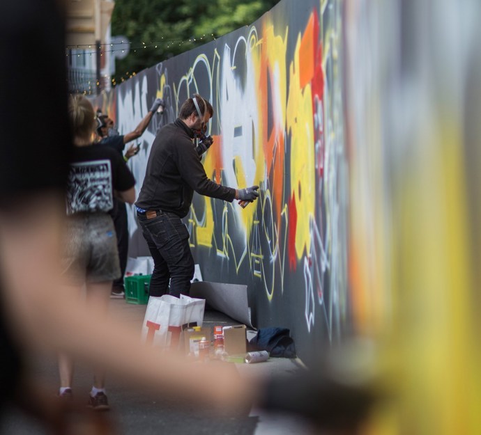 Flere kunstnere arbejder på en graffitivæg i Næstved bymidte