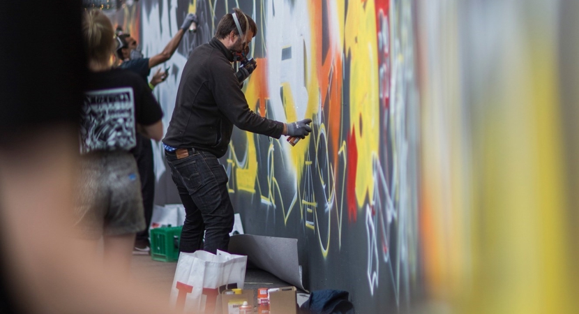 Flere kunstnere arbejder på en graffitivæg i Næstved bymidte
