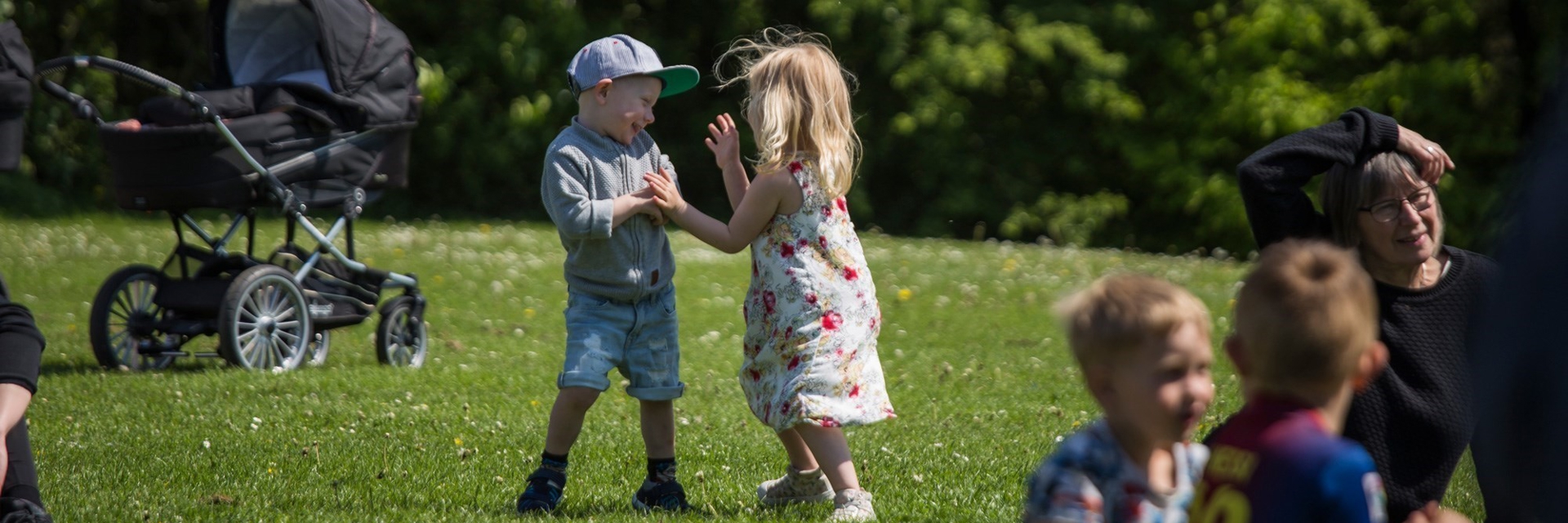 En dreng og en pige leger med hinanden, på græsareal i Mogenstrup